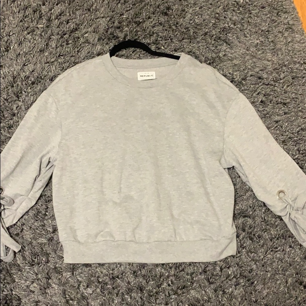 grey sweater with ties on the sleeve